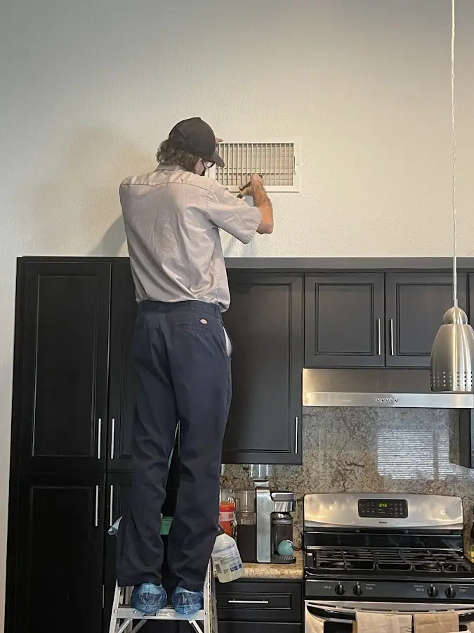 Technician inspecting an air vent during HVAC service in Universal City